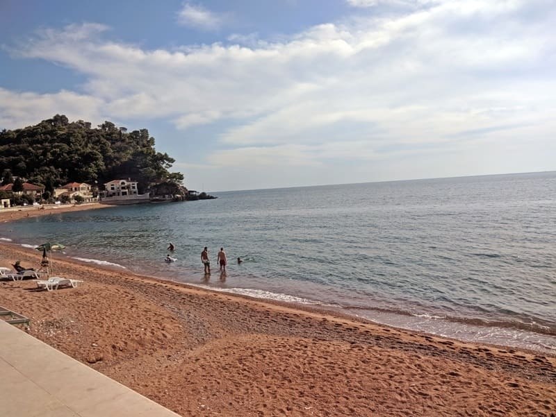 Спокойный пляж, море и зелёный мыс